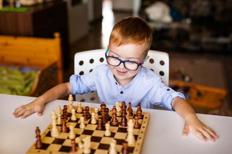 بچه روی میز در حال بازی شطرنج